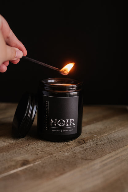 Deliciously Wickt all black long stick safety match being used to light a black NOIR soy candle.