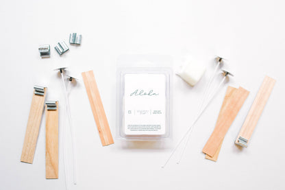 Deliciously Wickt Aloha soy wax melts surrounded by wooden sticks and candle-making accessories on a white background.