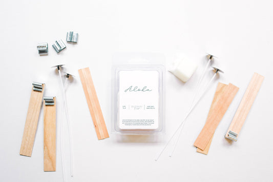 Deliciously Wickt Aloha soy wax melts surrounded by wooden sticks and candle-making accessories on a white background.