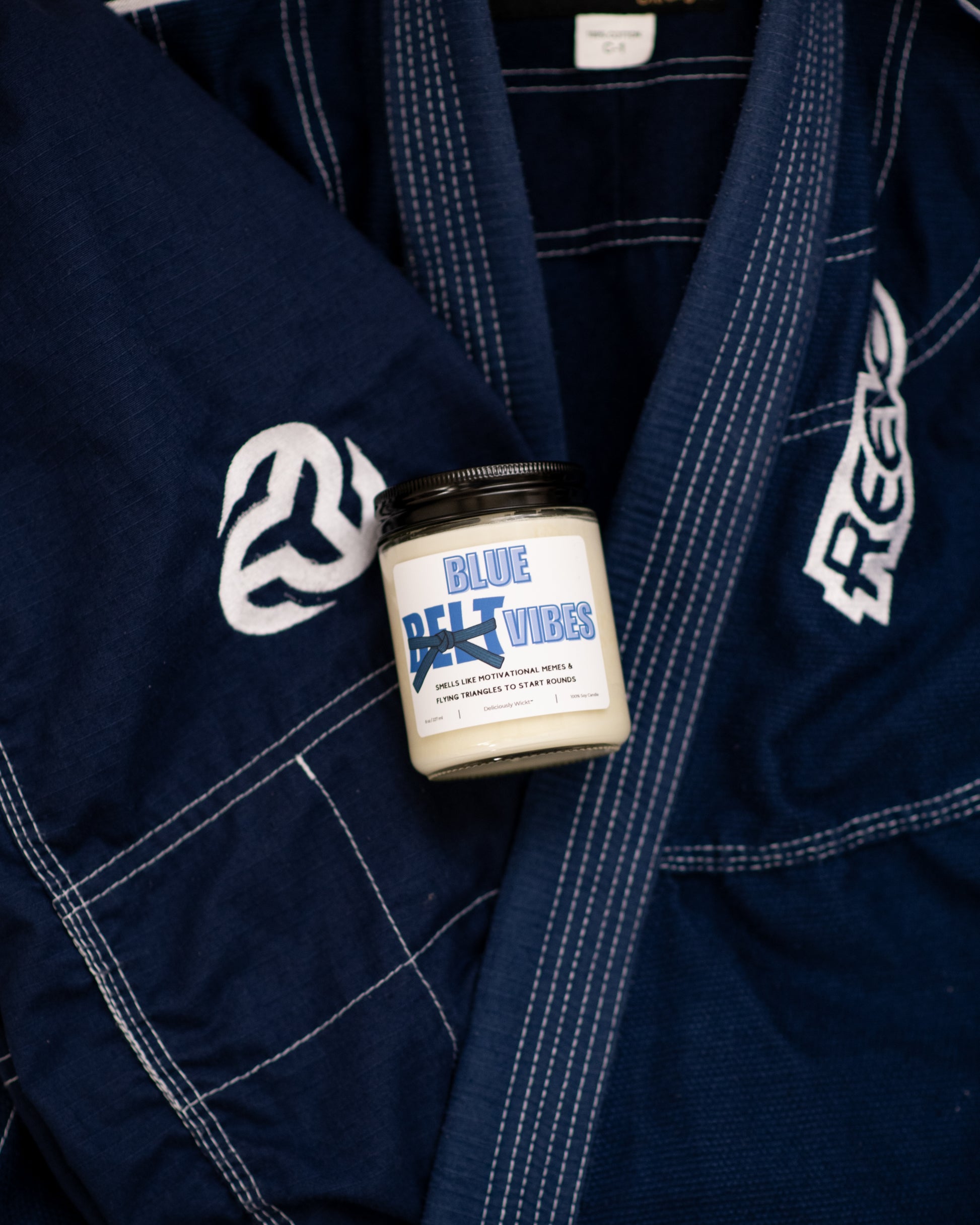 Blue Belt Vibes Jiu-Jitsu soy candle displayed on a blue gi