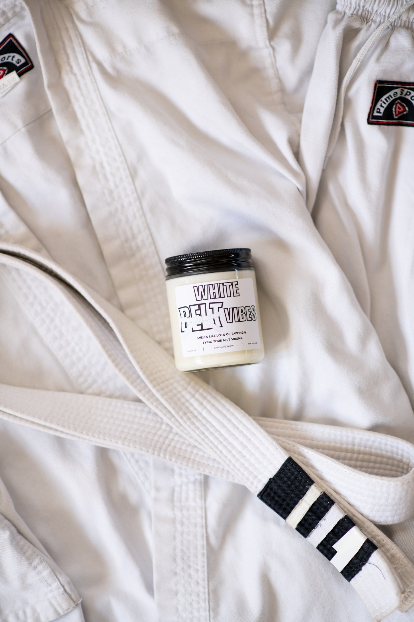 White Belt Vibes Jiu-Jitsu soy candle displayed on a white gi