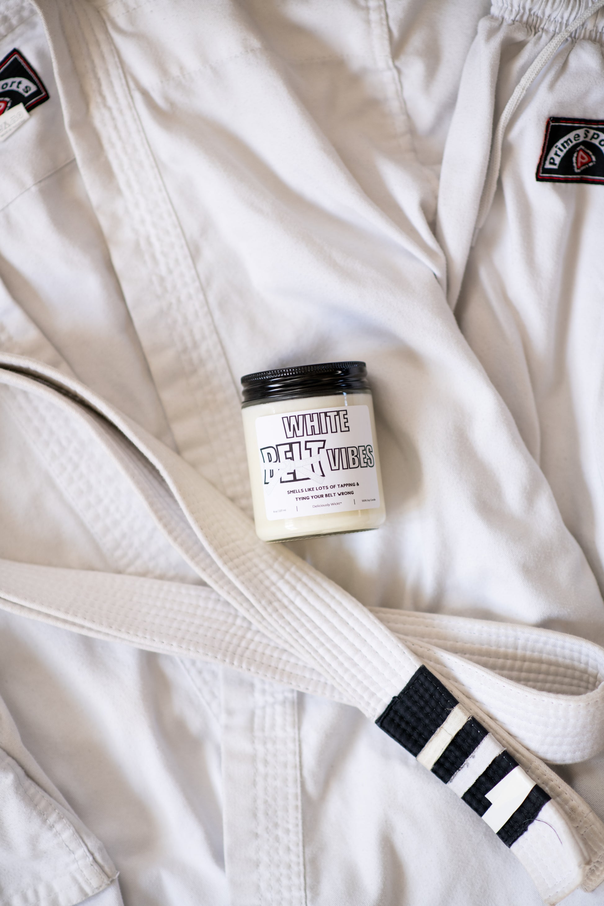 White Belt Vibes Jiu-Jitsu soy candle displayed on a white gi