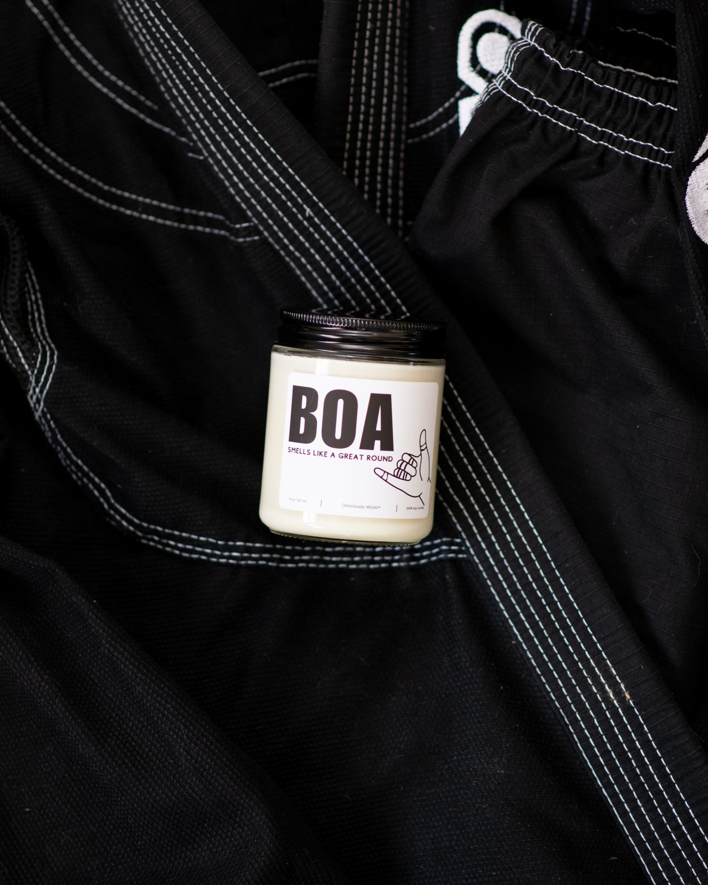 BOA Jiu-Jitsu soy candle with “Smells like a great round” label displayed on a black gi