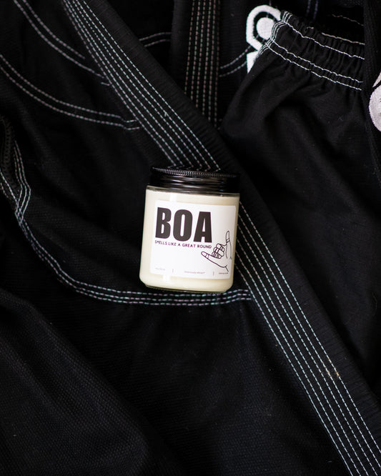BOA Jiu-Jitsu soy candle with “Smells like a great round” label displayed on a black gi