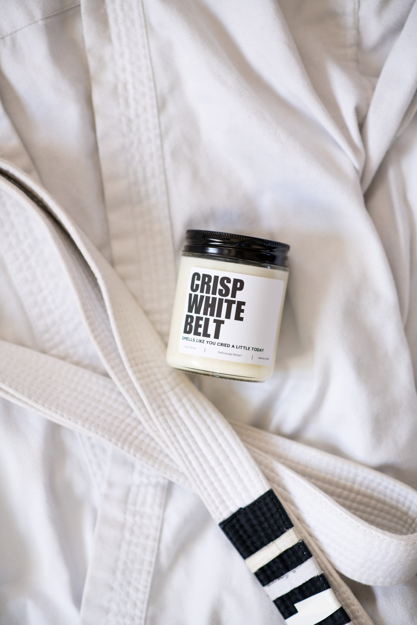 Crisp White Belt Jiu-Jitsu soy candle with “Smells like you cried a little today” label on a white gi