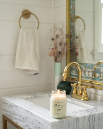 Deliciously Wickt Going, Going, Gone 16 oz mason jar soy candle displayed beside a bathroom sink.