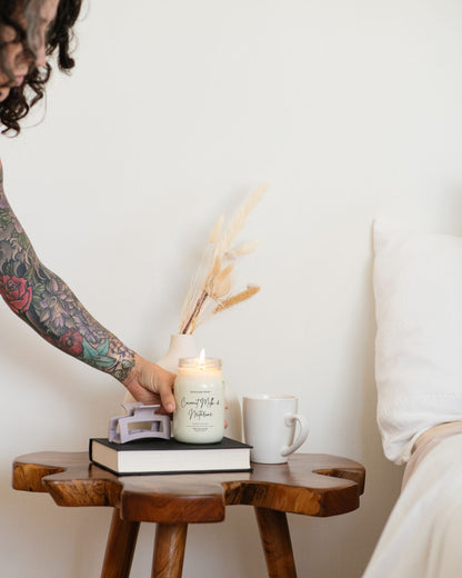 Deliciously Wickt Going, Going, Gone 16 oz mason jar soy candle displayed on a styled side table.