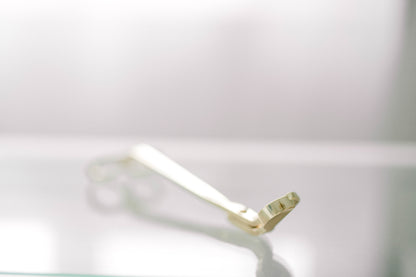 Deliciously Wickt gold metal candle wick trimmer displayed on a light background.
