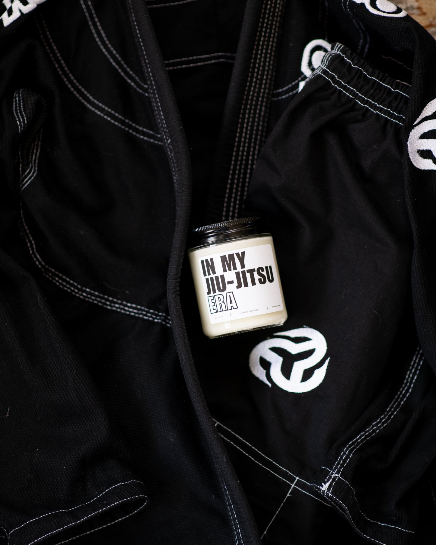 Deliciously Wickt In My Jiu-Jitsu Era 8 oz soy candle styled with black Jiu-Jitsu gi.