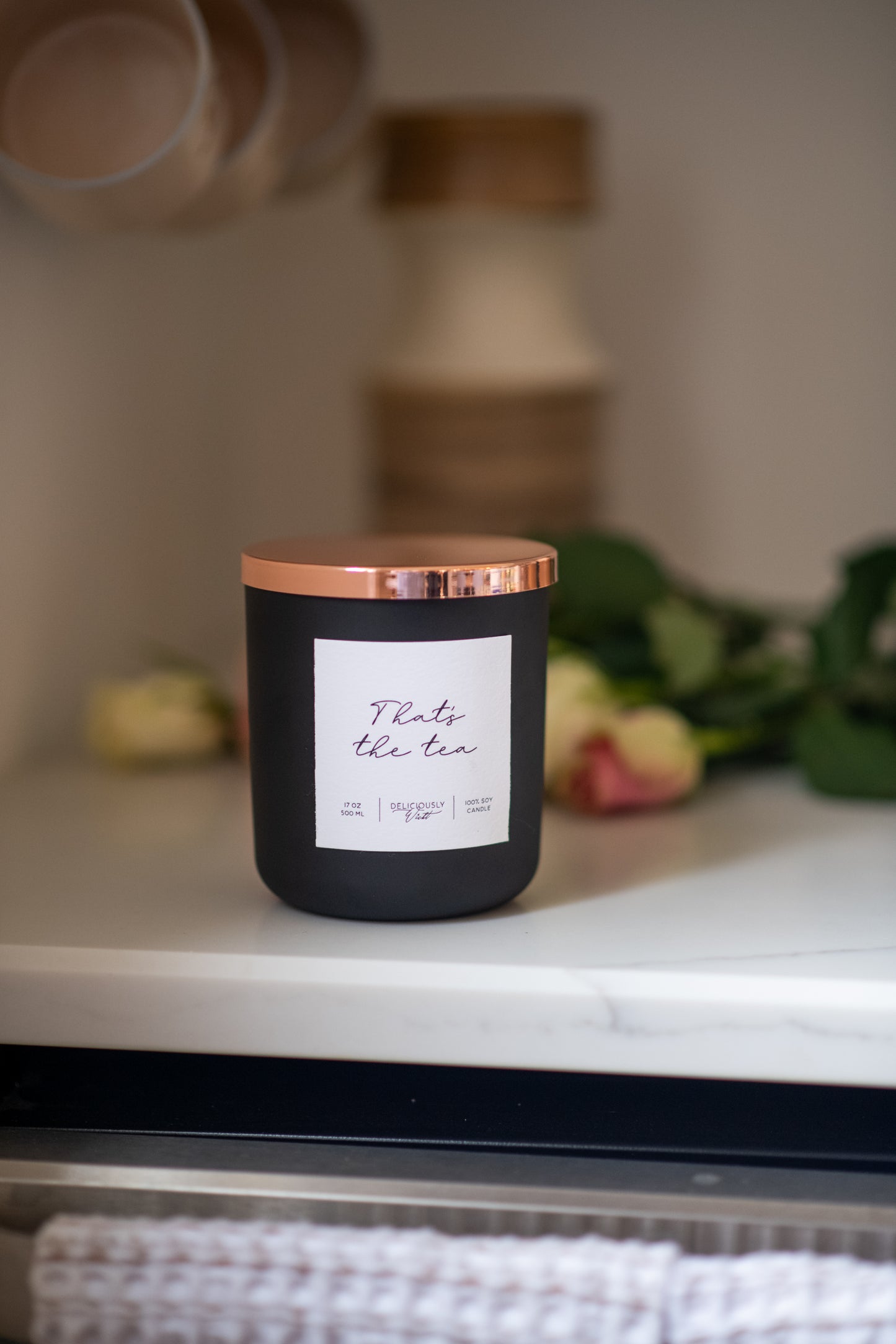 Deliciously Wickt matte black 17 oz soy candle displayed on a shelf in a warm, styled interior.