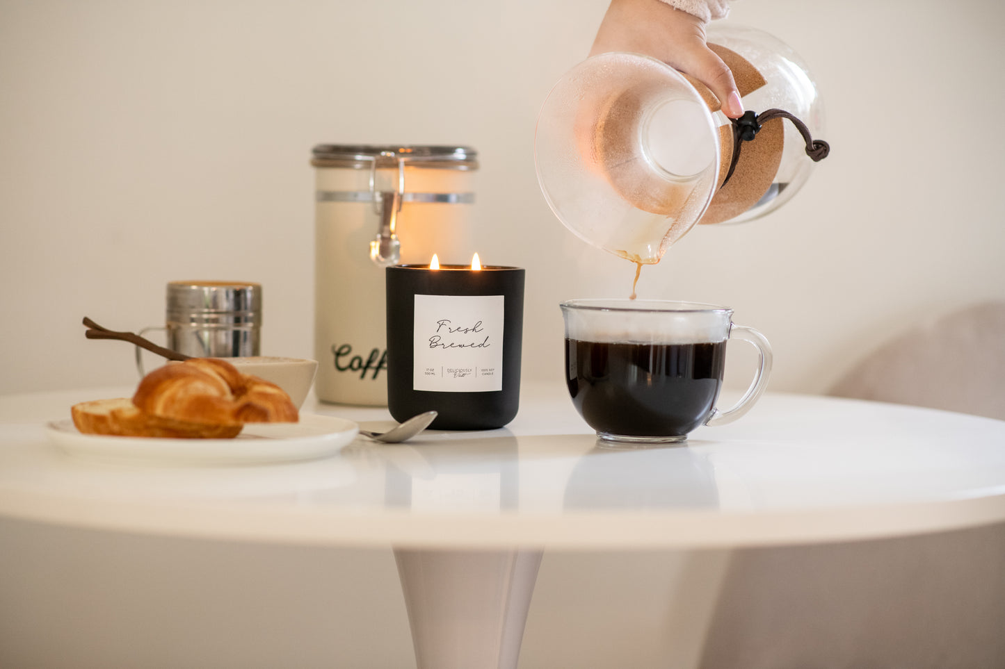 Deliciously Wickt matte black 17 oz soy candle styled on a white table in a bright room.