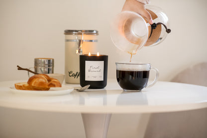 Deliciously Wickt matte black 17 oz soy candle styled on a white table in a bright room.