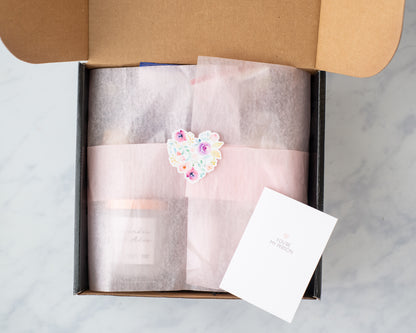 Deliciously Wickt mystery candle bundle wrapped in pink packaging with a card inside an open gift box