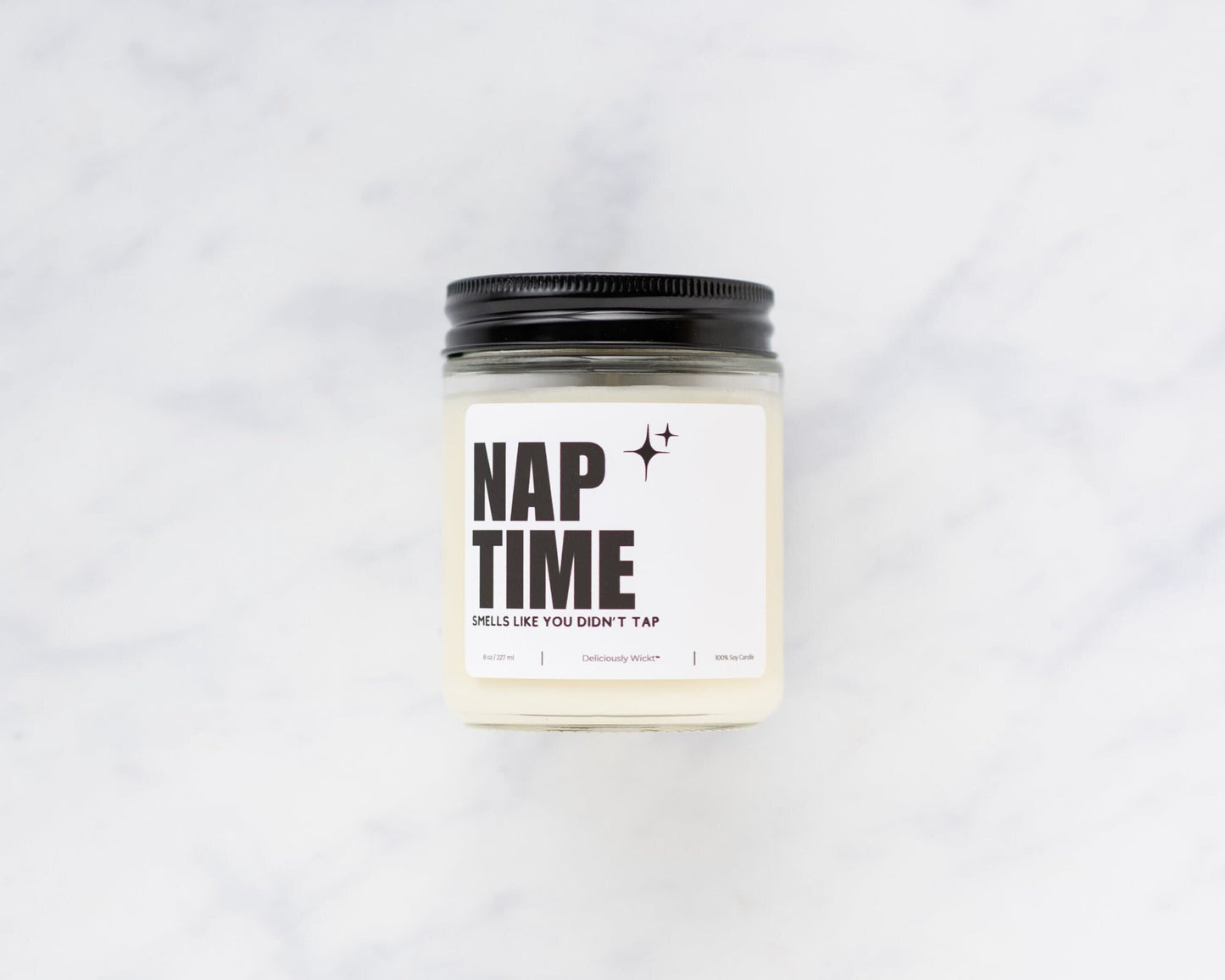Nap Time Jiu-Jitsu soy candle with “Smells like you didn’t tap” label on a marble background