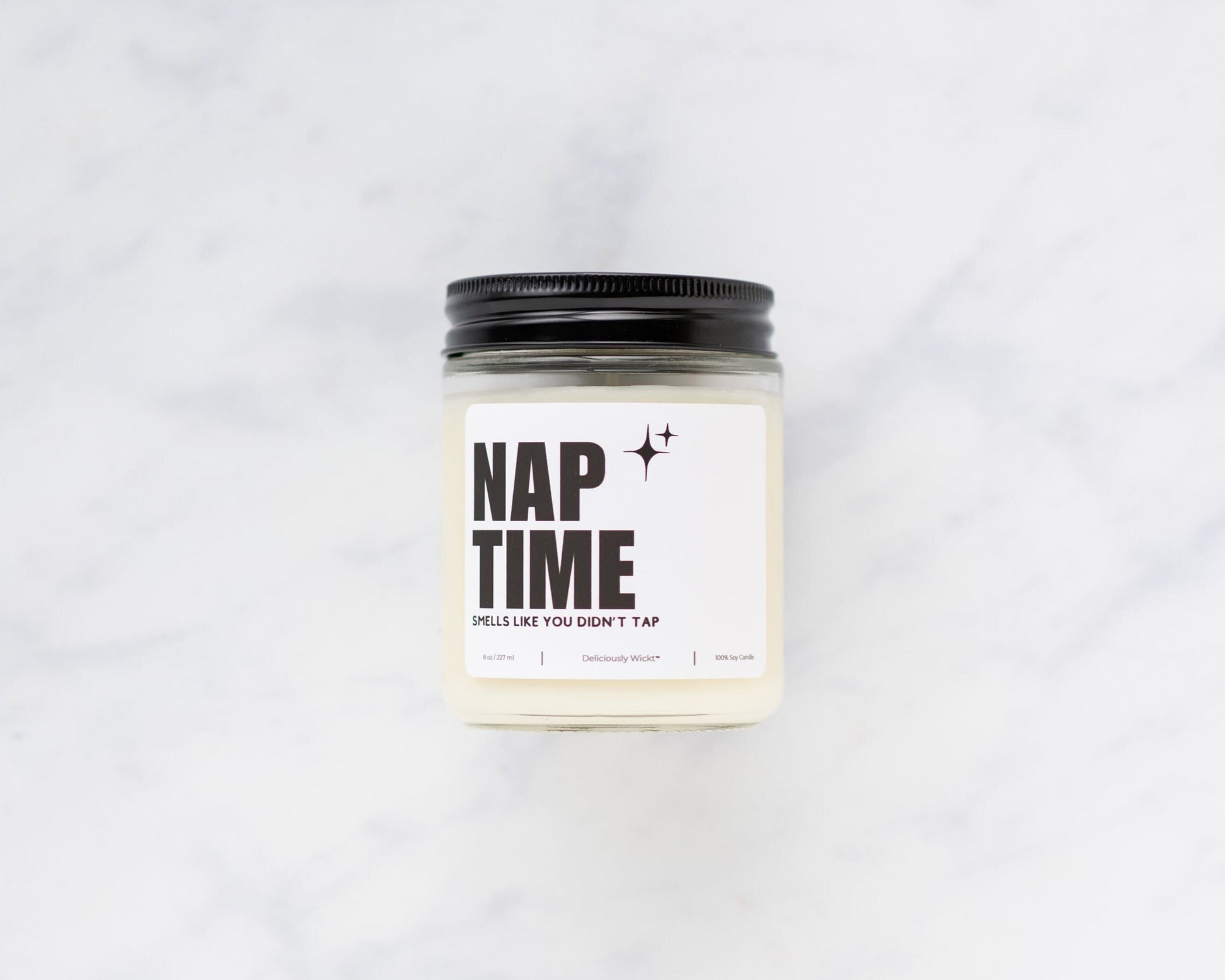 Nap Time Jiu-Jitsu soy candle with “Smells like you didn’t tap” label on a marble background