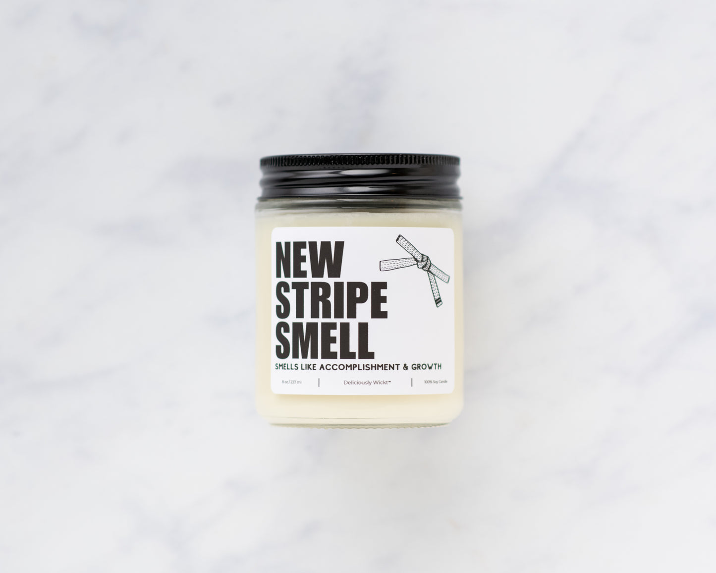 New Stripe Smell Jiu-Jitsu soy candle with “Smells like accomplishment & growth” label on a marble background