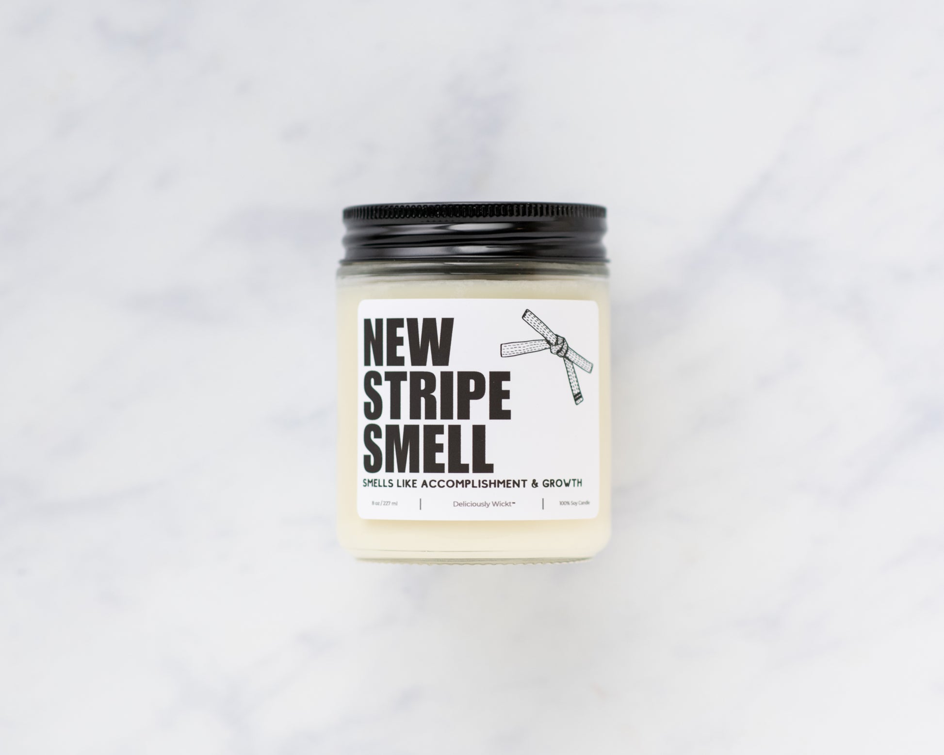 New Stripe Smell Jiu-Jitsu soy candle with “Smells like accomplishment & growth” label on a marble background
