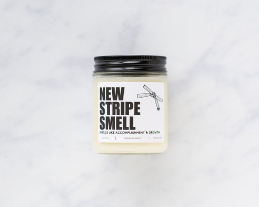 New Stripe Smell Jiu-Jitsu soy candle with “Smells like accomplishment & growth” label on a marble background