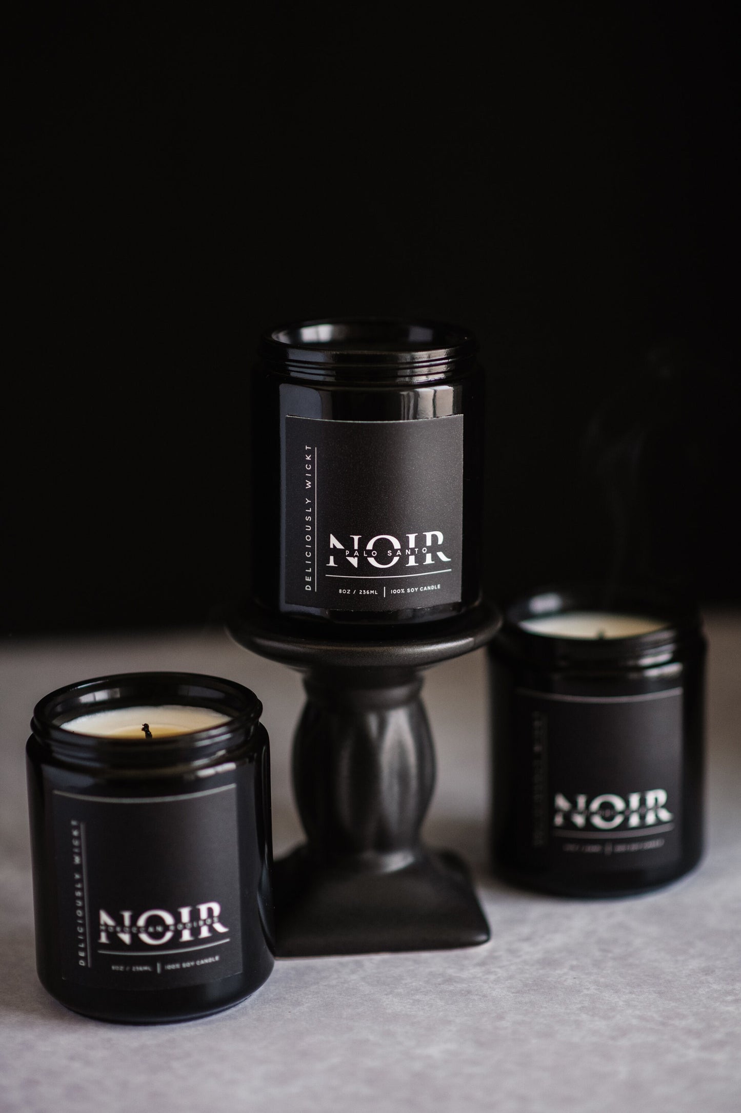 NOIR Trio of black soy candles grouped against a dark background