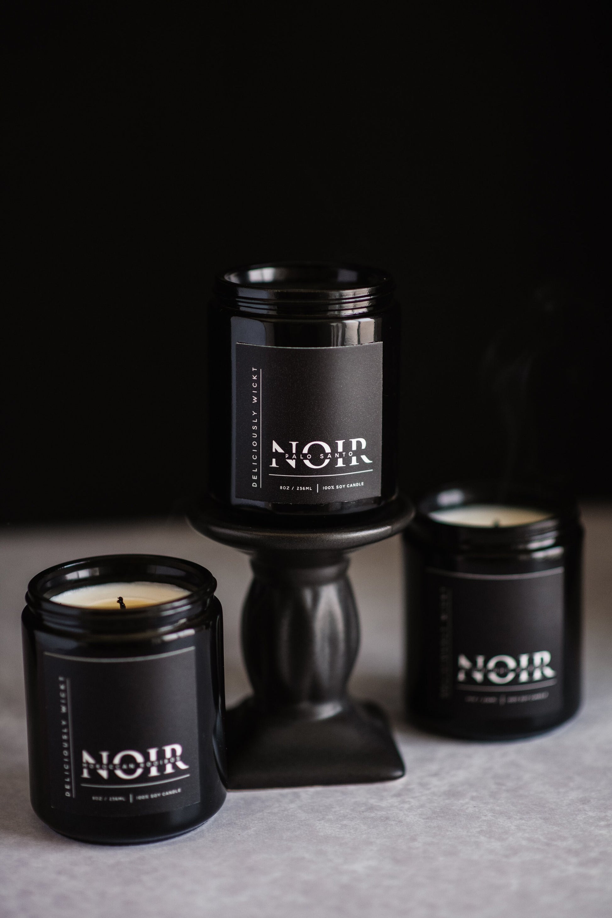 NOIR Trio of black soy candles grouped against a dark background