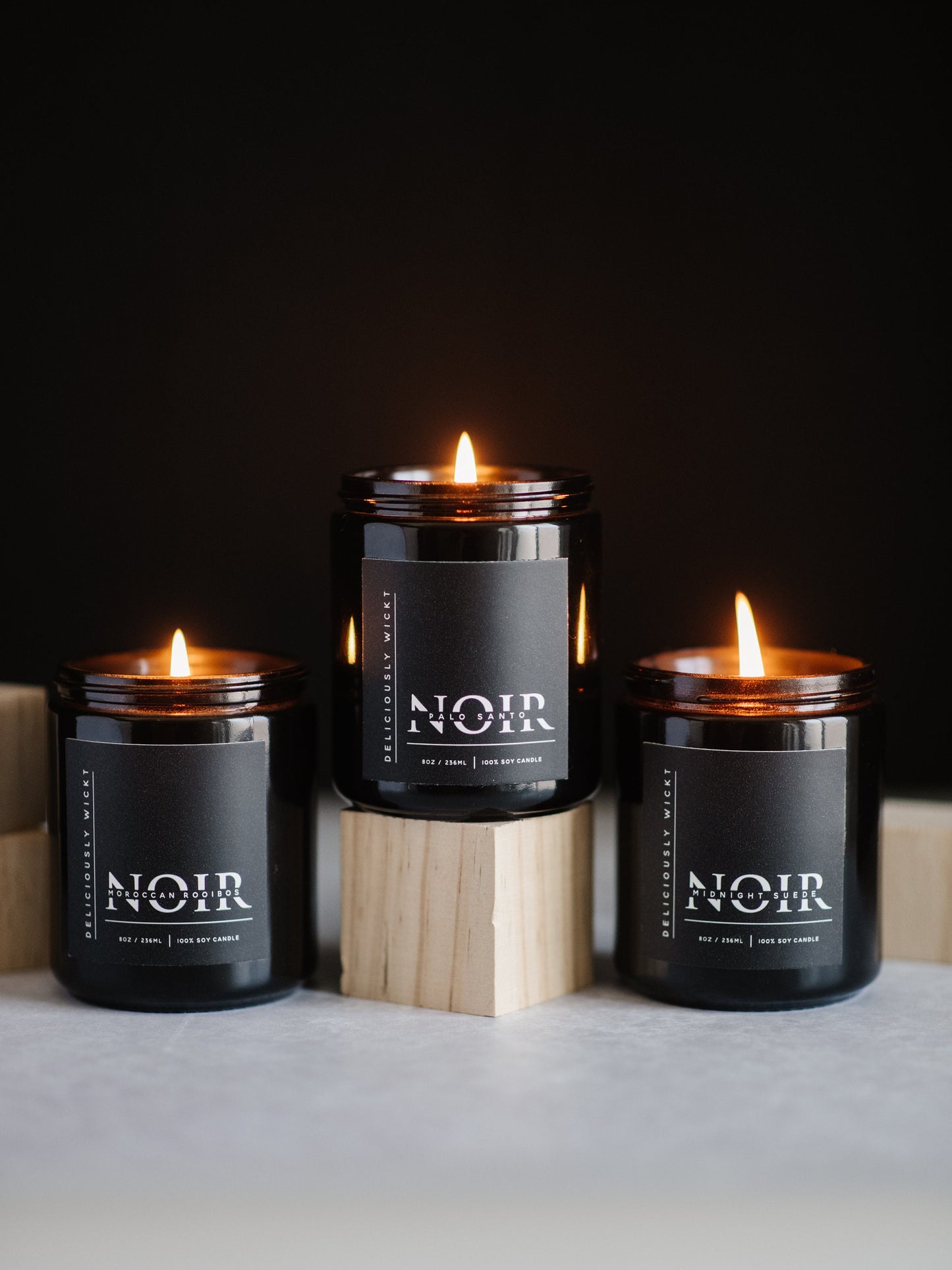 NOIR Trio of three 8 oz black soy candles burning in a styled display