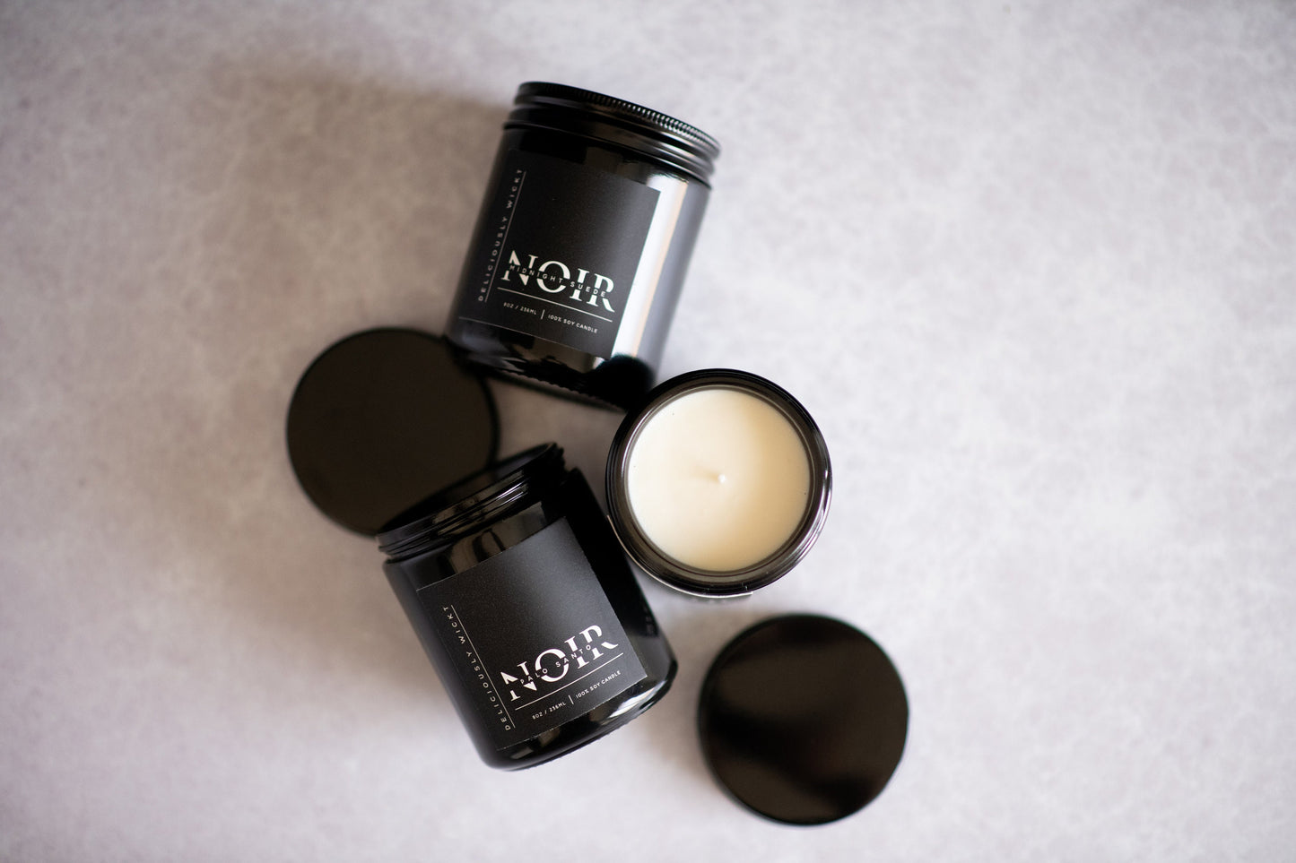 NOIR Trio of three black soy candles photographed from above with matte black lids