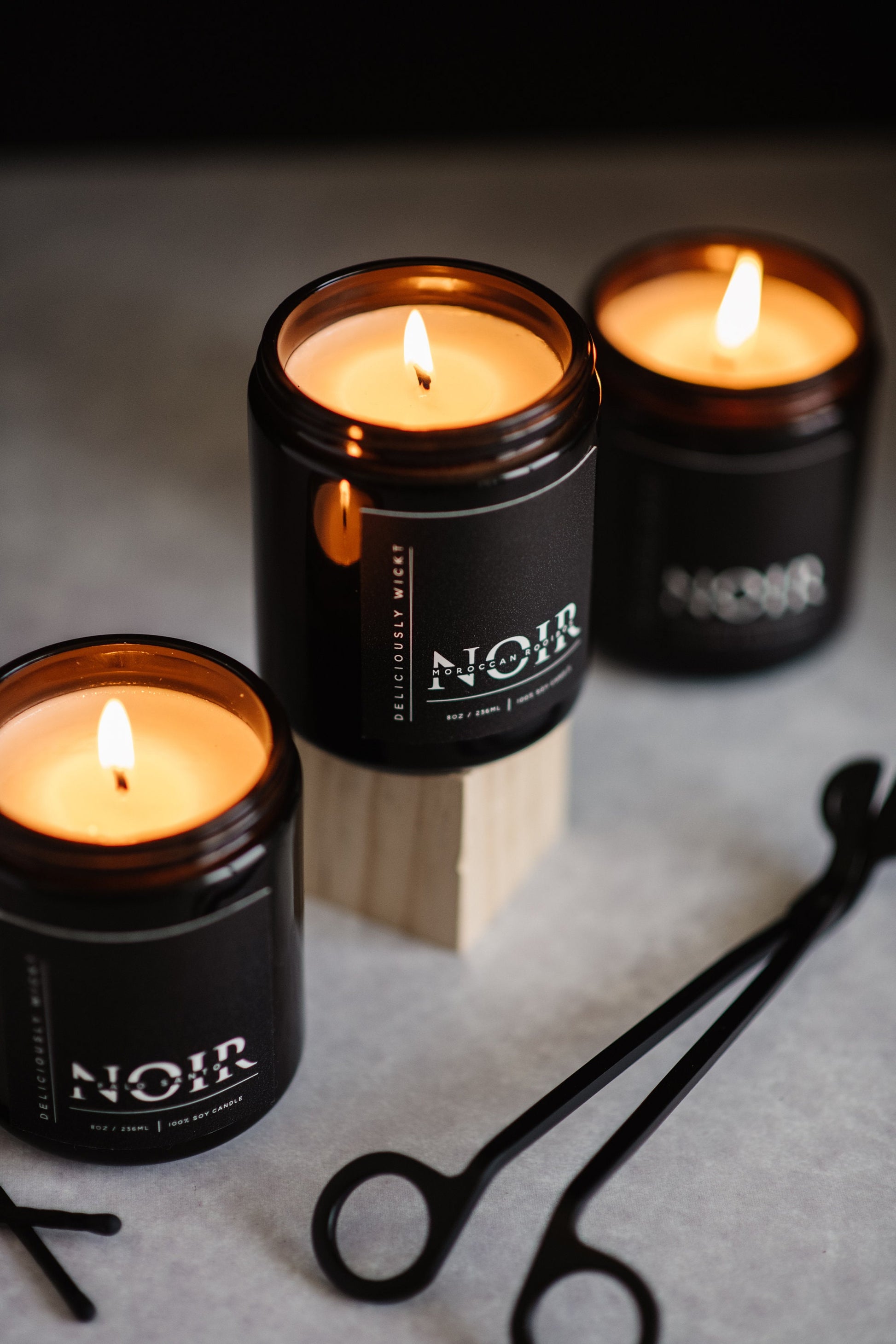 NOIR Trio of black soy candles styled with a black wick trimmer