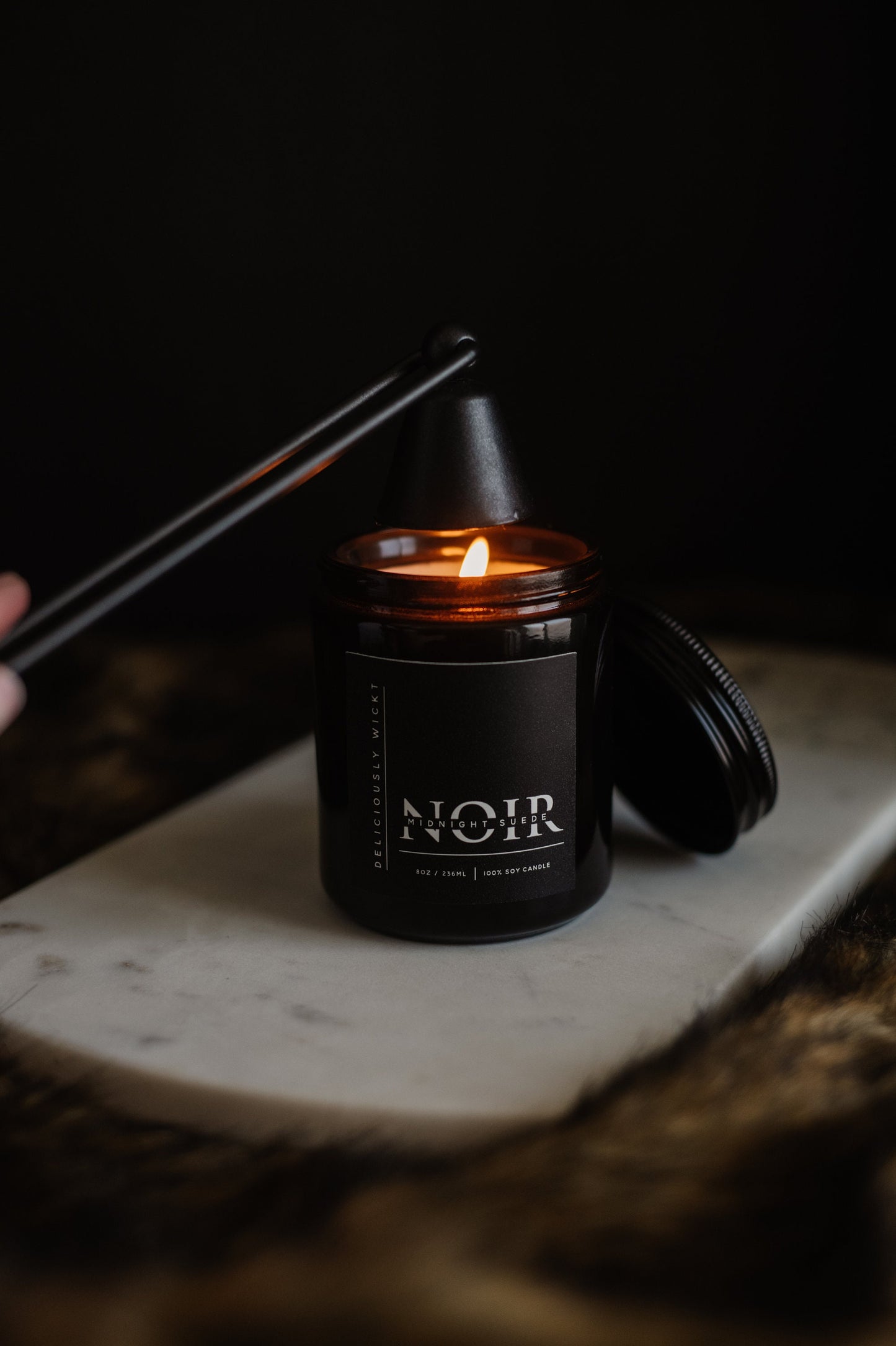 Lit NOIR black soy candle with matte black lid nearby