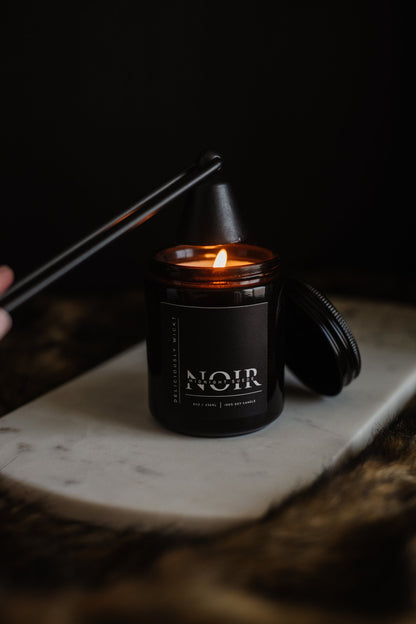 Lit NOIR black soy candle with matte black lid nearby