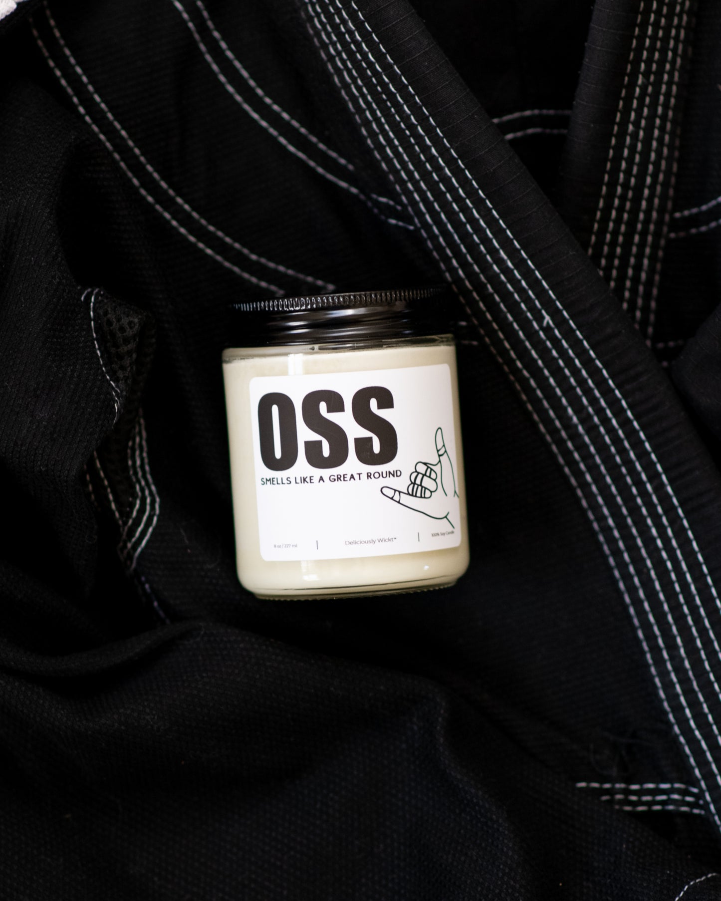 OSS Jiu-Jitsu soy candle with “Smells like a great round” label displayed on a black gi