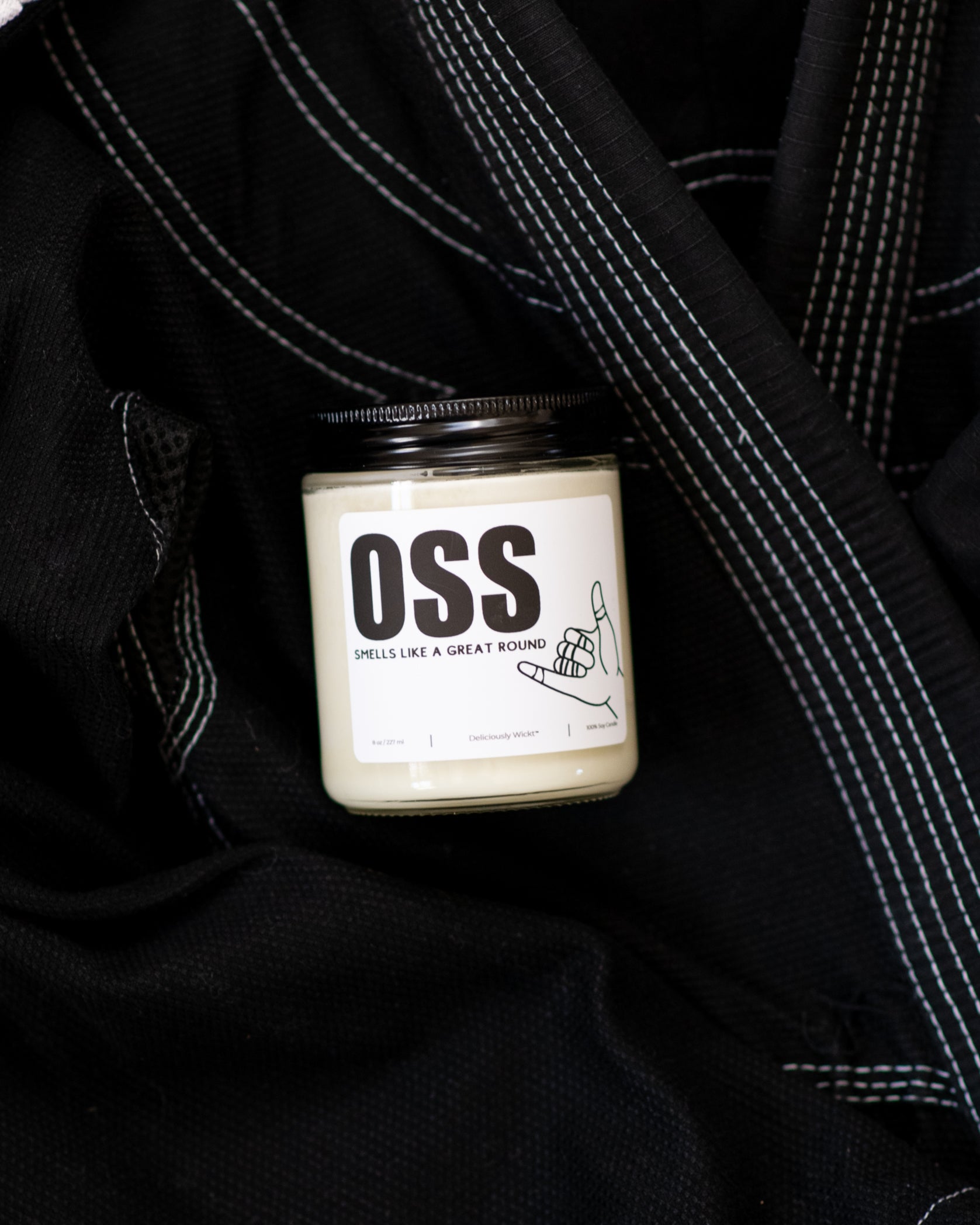 OSS Jiu-Jitsu soy candle with “Smells like a great round” label displayed on a black gi