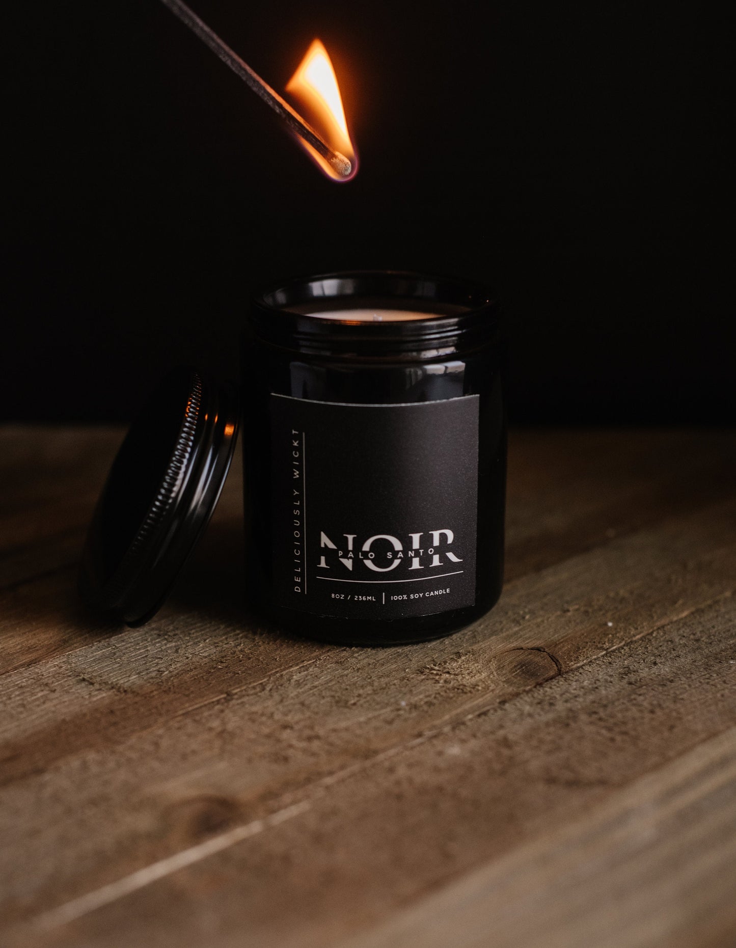 Lit Palo Santo NOIR soy candle showing the flame above the black vessel