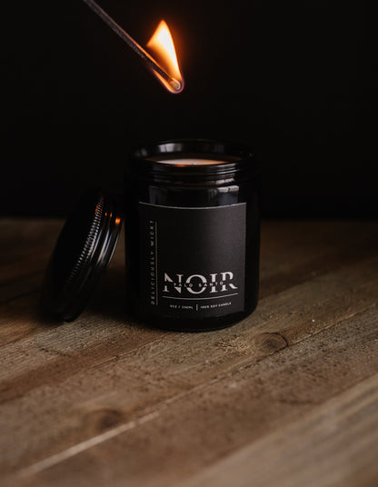 Lit Palo Santo NOIR soy candle showing the flame above the black vessel