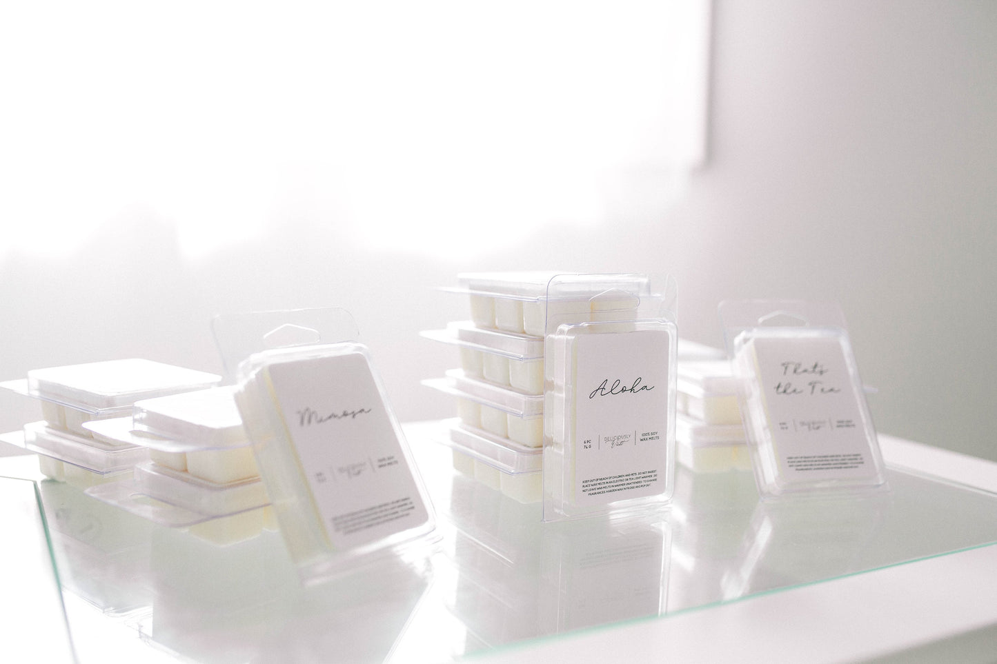 Assorted Deliciously Wickt scented soy wax melt packages displayed together on a light surface.