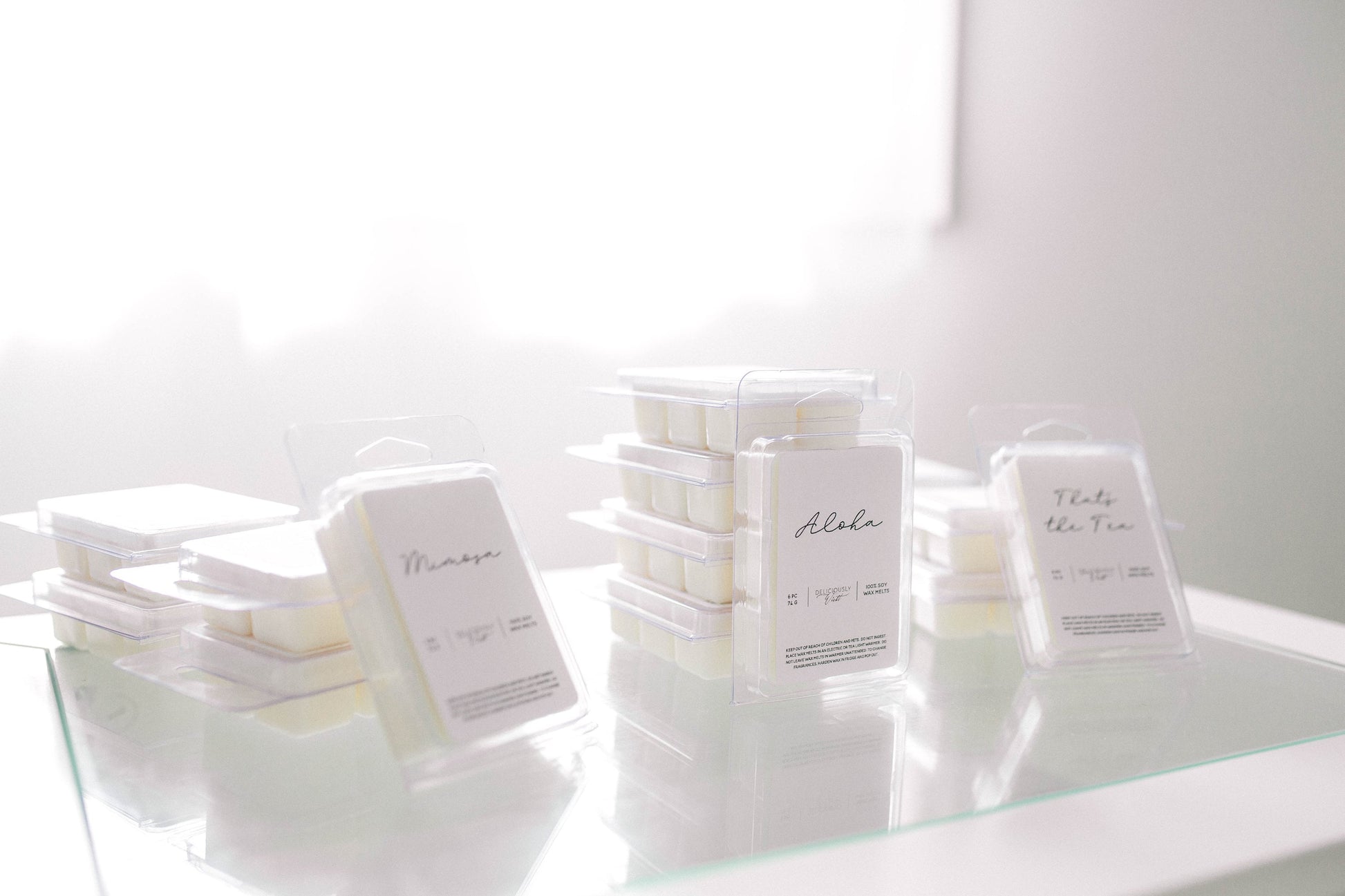 Assorted Deliciously Wickt scented soy wax melt packages displayed together on a light surface.