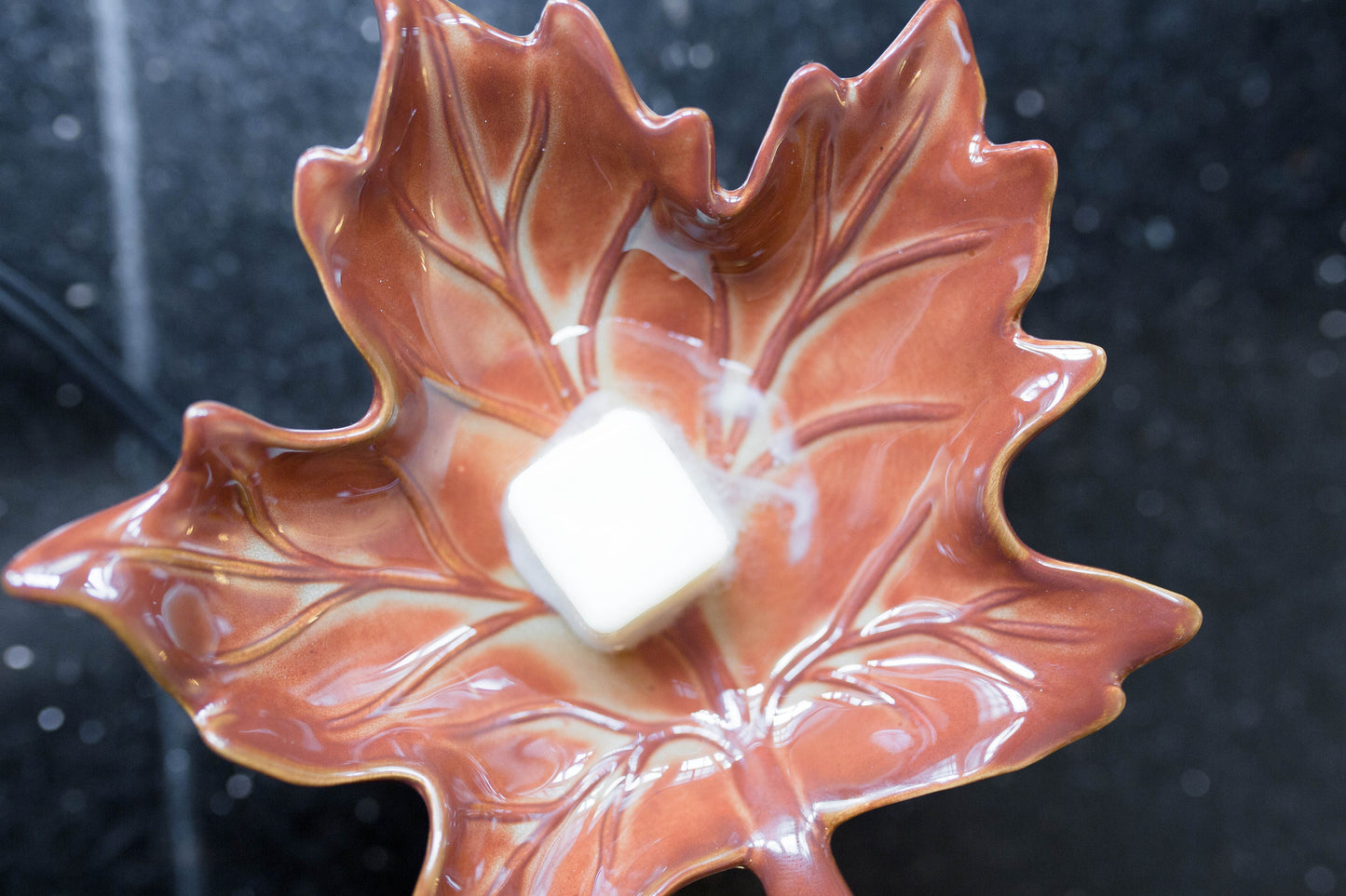 Deliciously Wickt soy wax melt cube warming in a decorative leaf-shaped wax warmer.