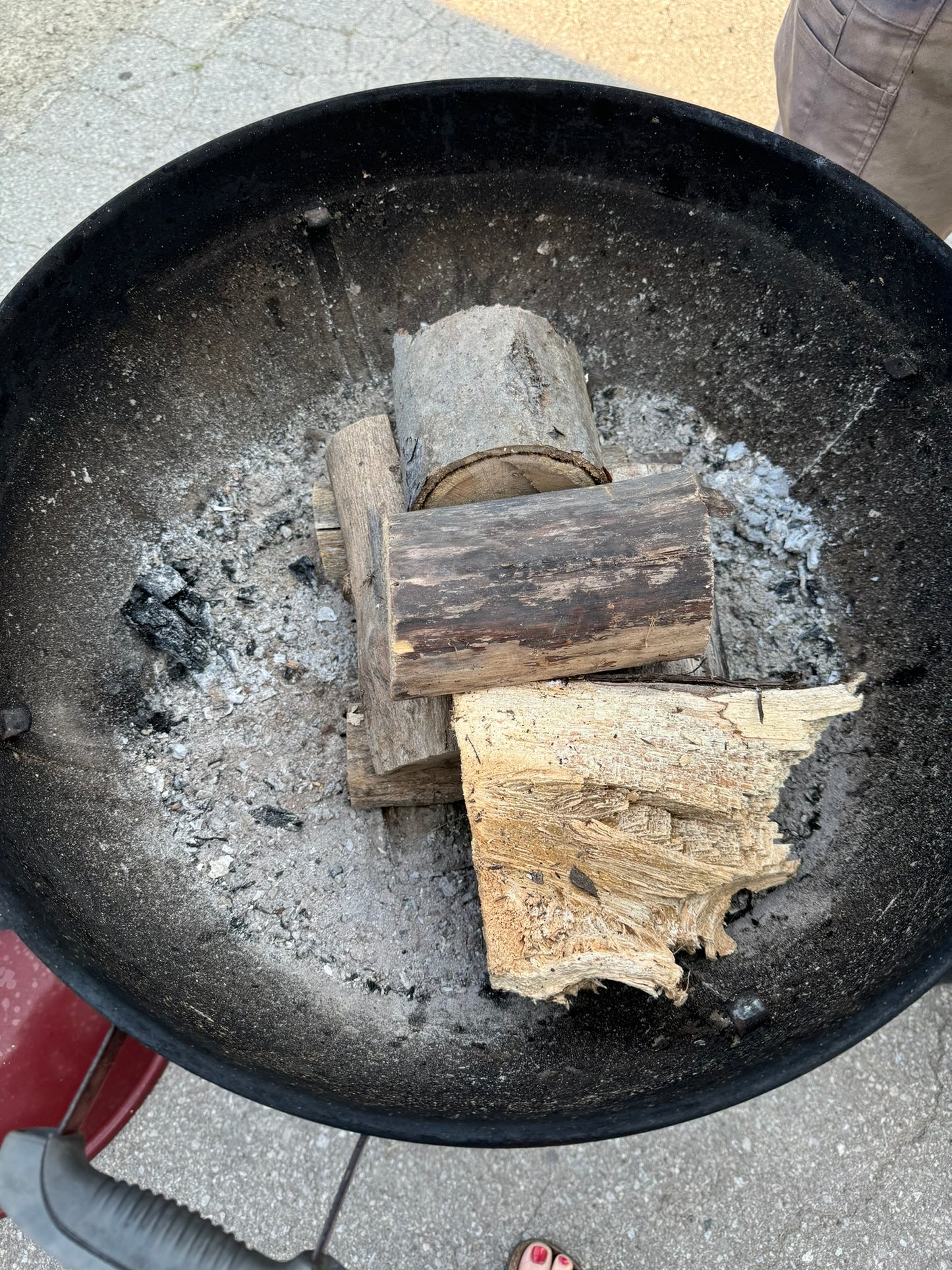 Deliciously Wickt Torcht aspen wood and soy wax firestarter pod positioned beneath firewood in a fire pit.
