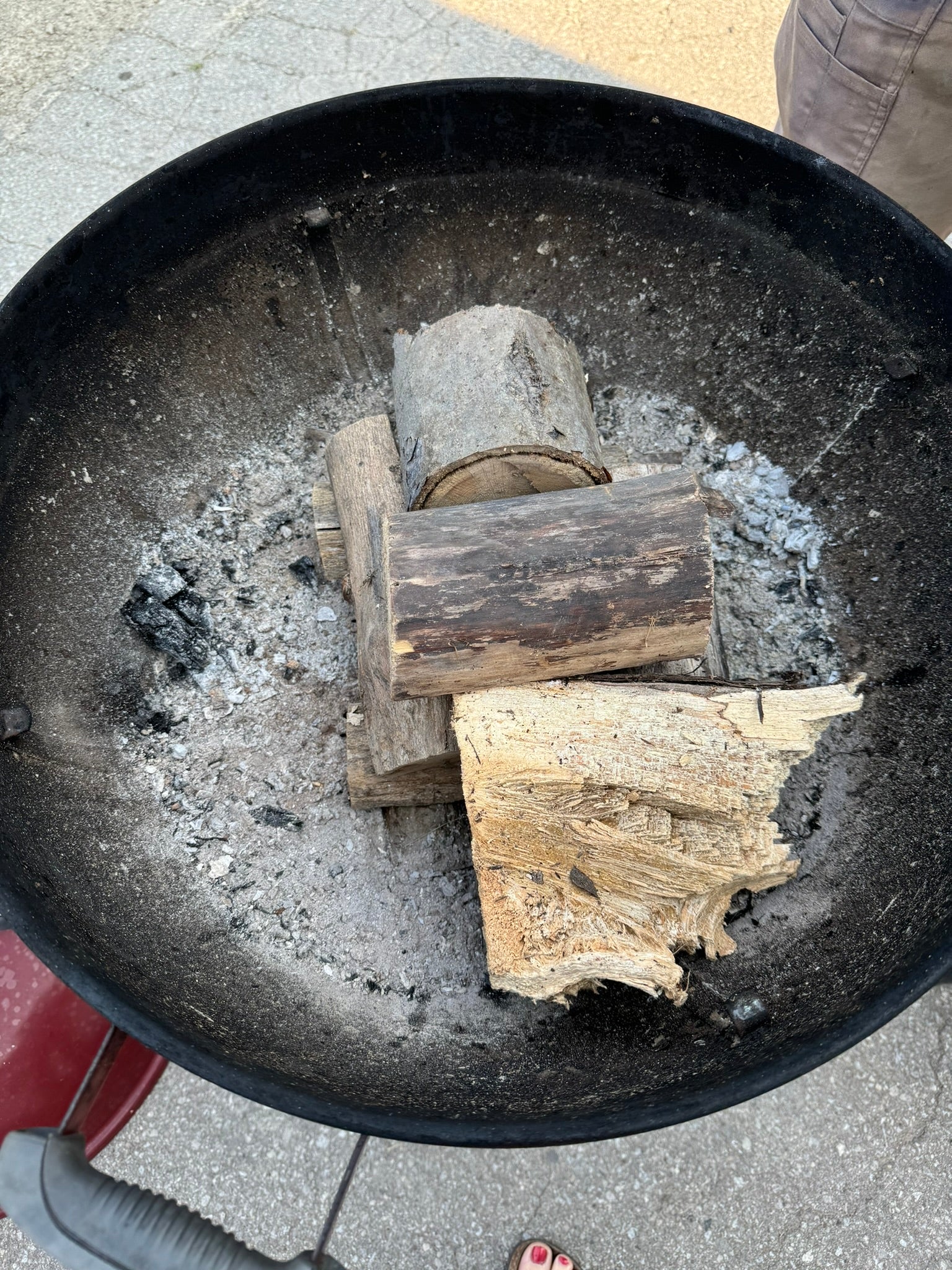 Deliciously Wickt Torcht aspen wood and soy wax firestarter pod positioned beneath firewood in a fire pit.