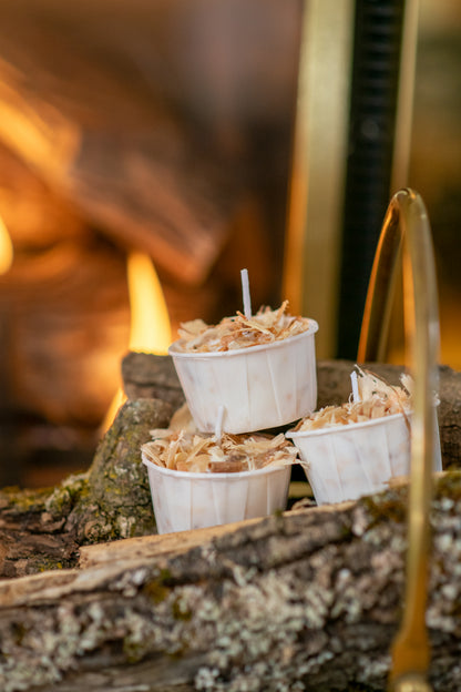 Deliciously Wickt Torcht aspen wood and soy wax firestarter pods beside a burning fireplace.