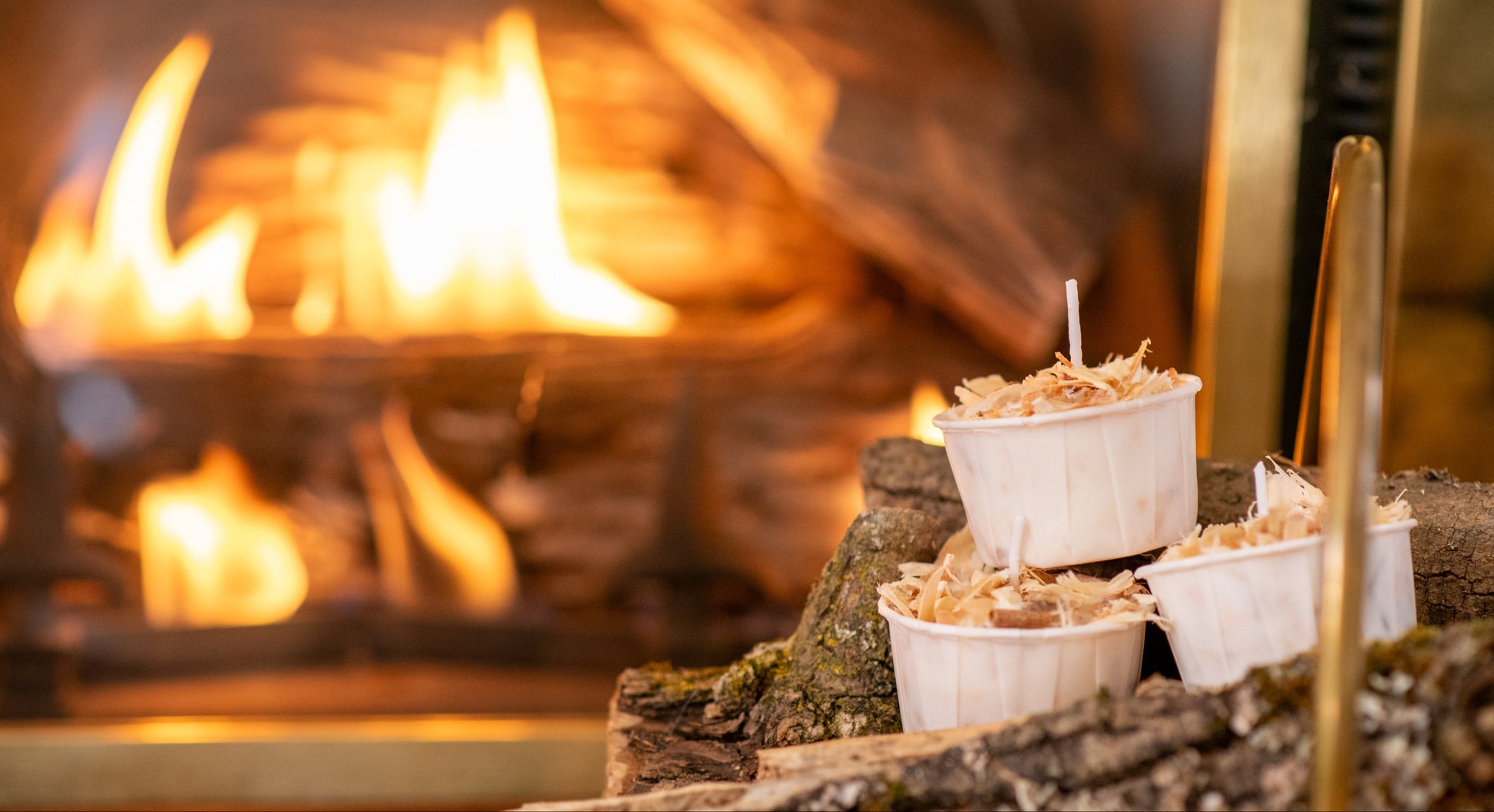 Deliciously Wickt Torcht soy wax firestarter pods displayed with firewood in front of a burning fire.